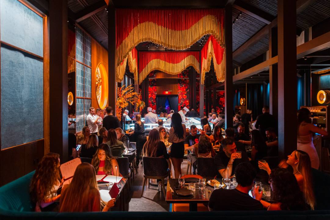 Guests dine under dramatic red-and-gold wave-like chandeliers in the grand main dining room at GEKKŌ,